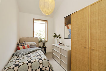 Burnholme Green internal bedroom photo showing a single bed with night stand, a set of drawers and a wardrobe, scandi style furniture and accessories decorate the room, on the far wall is a large external window