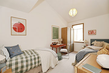 Burnholme Green internal bedroom photo showing a vaulted ceiling and space for 2 single beds, the room is also furnished with a desk and chair, some wall art and neutral décor, on the far wall is a large external