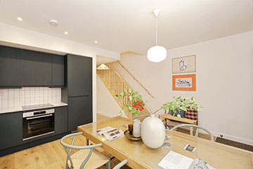 Burnholme Green internal kitchen photo showing dark grey units, integrated oven and hob, decorated with minimalist furniture, to the rear of the kitchen is a staircase leading upstairs