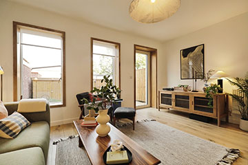 Burnholme Green internal photo of a living room, with large windows and a door leading to an outside space. Decorated with minimal scandi style furniture