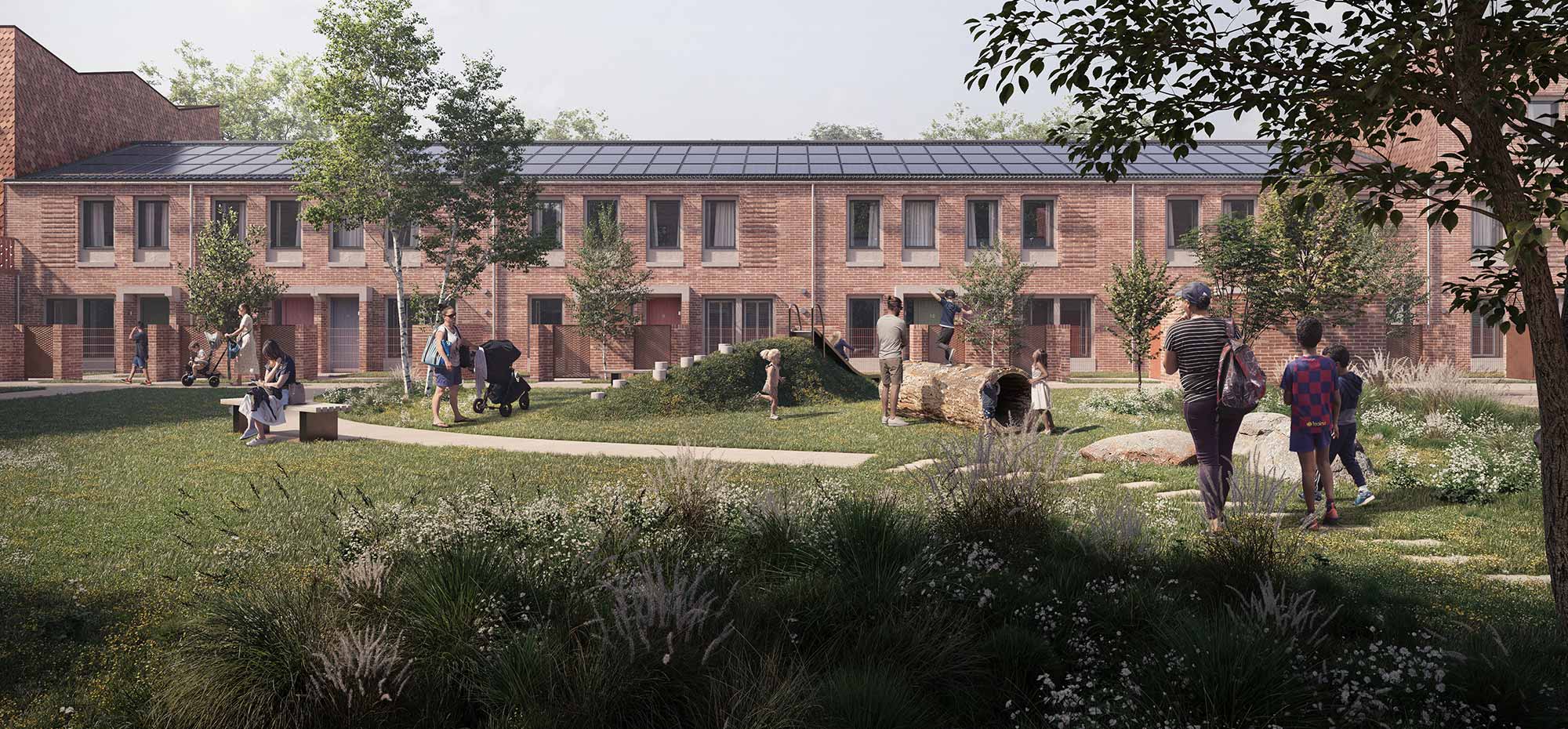 Front view of a modern three-storey red brick terraced Passivhaus with large rectangular windows, some featuring shutters on the ground floor. Children are playing on grass in front of the properties.